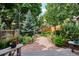 Landscaped backyard with a winding gravel path and mature trees at 1563 S Trenton Ct, Denver, CO 80231