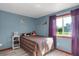 This quaint bedroom features bright purple accents, light walls, and a well-lit window at 18553 County Road 5, Berthoud, CO 80513