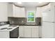 Cozy kitchen with white cabinets, modern backsplash, and a bright window view at 5455 Dudley Ct, Arvada, CO 80002
