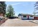 Exterior view of a cozy home with a red front door and a paved driveway, close to mature trees at 8540 Corona St, Denver, CO 80229