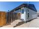 Rear entrance shows gray brick, concrete steps, wood fence, and modern gray roof on a sunny day at 8540 Corona St, Denver, CO 80229