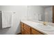 Bright bathroom features a vanity with white countertop and wood cabinets, a sink with gold fixtures, and a large mirror at 3407 S Ammons St # 20-1, Lakewood, CO 80227