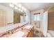 Well-lit bathroom with double sinks, granite counters, and a tiled shower and bath combination at 1008 Yeager Dr, Longmont, CO 80501