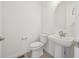 Bright half bathroom featuring a modern pedestal sink and round mirror at 1257 Rhett Dr, Erie, CO 80026