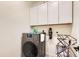 A modern laundry room features a front-load washer, upper cabinets, and sleek design elements for efficient laundry chores at 222 Fox St, Bennett, CO 80102