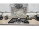 Close-up of the cooktop with custom tile backsplash and modern range hood at 3103 W 18Th Ave, Denver, CO 80204