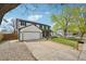 Exterior of the home with attached garage, manicured lawn, mature trees, and paved driveway at 1001 S Nucla St, Aurora, CO 80017
