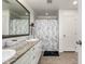 Bright bathroom featuring double sinks with granite countertops, decorative mirror, and shower with floral curtain at 9350 Dunraven St, Arvada, CO 80007