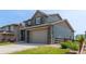 Stylish home exterior featuring a two-car garage, stone accents, and well-manicured lawn with a wooden fence at 9350 Dunraven St, Arvada, CO 80007