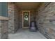 Inviting front porch with stone surround, decorative wreath on the door, and a comfortable chair for relaxing at 9350 Dunraven St, Arvada, CO 80007