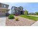 Well-maintained front yard features decorative rock landscaping and lush green grass leading to a stone accented home at 9350 Dunraven St, Arvada, CO 80007