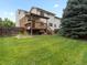 View of the home's backyard featuring a well-maintained lawn, wooden deck, and privacy fence at 2040 Yarrow St, Lakewood, CO 80214