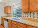 Well-lit kitchen features tile backsplash, stainless sink, granite countertops, and wood cabinets at 2040 Yarrow St, Lakewood, CO 80214