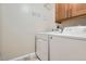 Bright laundry room is equipped with a washer, dryer, and overhead cabinets for storage at 5191 S Nepal Way, Centennial, CO 80015