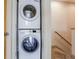 Convenient laundry closet with stacked washer and dryer units, located near carpeted stairs at 1632 N Gilpin St, Denver, CO 80218