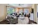 Cozy living room with comfortable leather seating, large windows, elegant curtains, hardwood floors, and a ceiling fan at 1201 Trout Creek Cir, Longmont, CO 80504