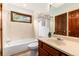 Bathroom with a shower-tub combination, neutral tile, wood cabinets, and a window for natural light at 4 Oakmont Ln, Littleton, CO 80127