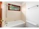 Bathroom with a shower-tub combination, neutral tile, and a window for natural light at 4 Oakmont Ln, Littleton, CO 80127