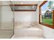 Bright bathroom featuring a large tub, walk-in shower, and a scenic view from the wood-trimmed window at 4 Oakmont Ln, Littleton, CO 80127