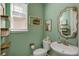 Stylish powder room featuring a decorative mirror, sink, toilet, and soft green walls at 892 High Point Trl, Elizabeth, CO 80107