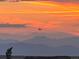 A plane flies in the sunset, painting the mountains in the distance with orange and pink light at 1609 S Catawba Cir, Aurora, CO 80018