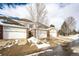 View of townhome garages with brick accents, individual driveways, and snow-covered landscaping at 3383 Mount Royal Dr # 46, Castle Rock, CO 80104