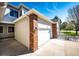 Attached two-car garage featuring red brick, white doors, and a concrete driveway on a sunny day at 3383 Mount Royal Dr # 46, Castle Rock, CO 80104