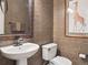 Stylish powder room features patterned wallpaper, a pedestal sink, and decorative mirror at 9531 Desert Willow Way, Highlands Ranch, CO 80129