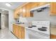 Functional kitchen featuring wood cabinets, white appliances, and tiled flooring at 2500 S York St # 115, Denver, CO 80210