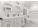 Bright bathroom with double vanity, round mirrors, tile backsplash, and a shower-tub combination at 2426 Ames St, Edgewater, CO 80214