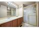 Bathroom with double sink vanity, bright lighting, and glass enclosed shower with gold trim at 11100 Callaway Ct, Parker, CO 80138