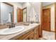 Bathroom boasts double sinks, stone countertops, framed mirrors, and wooden cabinet storage at 2597 Oak Vista Ct, Castle Rock, CO 80104
