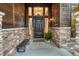 Inviting front entrance with a dark wood door, stone accents, sidelights, and a charming bench at 2597 Oak Vista Ct, Castle Rock, CO 80104