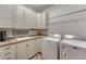 Bright laundry room with white cabinetry, countertop space, sink, and modern washer and dryer units at 2597 Oak Vista Ct, Castle Rock, CO 80104