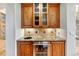 Charming wet bar featuring granite countertop, wine fridge, sink, and ample wood cabinet storage with glass doors at 2597 Oak Vista Ct, Castle Rock, CO 80104