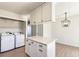 Bright kitchen featuring a quartz island, modern lighting, and a laundry closet with washer and dryer at 1620 S Ivory Cir # C, Aurora, CO 80017