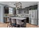 Modern kitchen featuring dark cabinets, stainless steel appliances, an island with seating, and stylish backsplash at 13322 Meadow Park Ln, Broomfield, CO 80020