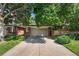 Two-car garage in a brick home framed by mature trees and manicured landscaping at 2552 E Alameda Ave # 74, Denver, CO 80209