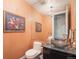 Unique powder room with a vessel sink, dark vanity, a hanging chandelier, and peach colored walls at 2552 E Alameda Ave # 74, Denver, CO 80209