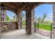 Covered patio featuring stone columns, iron gate and mature landscaping with lake views at 2317 Primo Rd # A, Highlands Ranch, CO 80129
