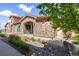 Charming stone townhouse exterior featuring a quaint patio and river rock landscaping under a partly cloudy sky at 2317 Primo Rd # A, Highlands Ranch, CO 80129
