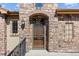 Inviting stone entryway with a secure screen door, brick archway, and classic wrought iron accents at 2317 Primo Rd # A, Highlands Ranch, CO 80129