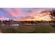 Panoramic view of the lush golf course with serene pond and colorful sunset sky overhead at 9180 E Center Ave # 9D, Denver, CO 80247