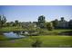 Scenic view of the golf course featuring lush greenery, a pond, and trees in the community at 9180 E Center Ave # 9D, Denver, CO 80247