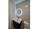 Modern bathroom featuring floating vanity with black accents and a large, illuminated round mirror at 17605 E Temple Dr, Aurora, CO 80015