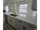 Bright kitchen with a large island featuring white cabinets, a stainless steel dishwasher and sleek black hardware at 17605 E Temple Dr, Aurora, CO 80015