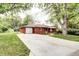Quaint single-story red brick home boasts a spacious driveway, lush greenery, and an attached garage at 6340 Quay St, Arvada, CO 80003