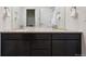 Bathroom featuring dual sinks, granite countertop, dark cabinets, and mirrors with a white door and hardware at 14419 Dahlia St, Thornton, CO 80602