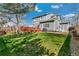A spacious backyard featuring a well-maintained lawn, a charming red deck, and mature trees, ideal for outdoor living at 9898 Mulberry Way, Highlands Ranch, CO 80129