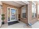 Charming front porch with brick siding, a secure door, and manicured greenery on either side at 13277 Elizabeth St, Thornton, CO 80241